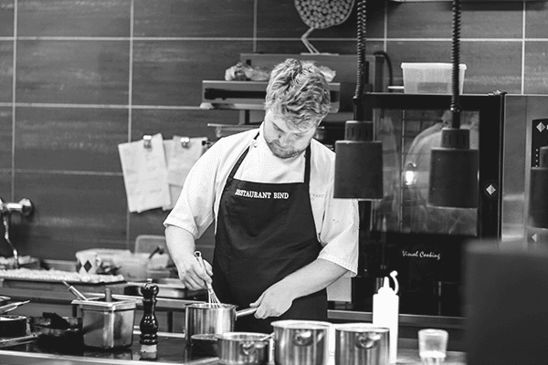 A chef stirs the sauce, enjoying being in his dream job.