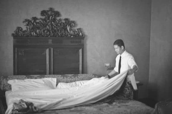 Housekeeper making the bed in a guest room at a luxury hotel.
