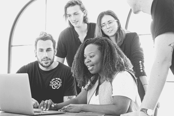 Sales and marketing manager working with her team and going over something on the computer.
