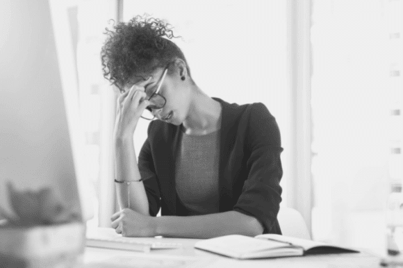 A women pinches her brow in clenched thought as she considers taking the plunge and resigning.